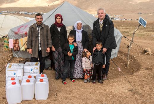 Kamals familie fik varmeovne og brændstof fra Mission Øst. Danske Kim Hartzner og Kamals familie står foran det telt, som har været familiens hjem i 14 måneder. Foto: Peter Eilertsen.